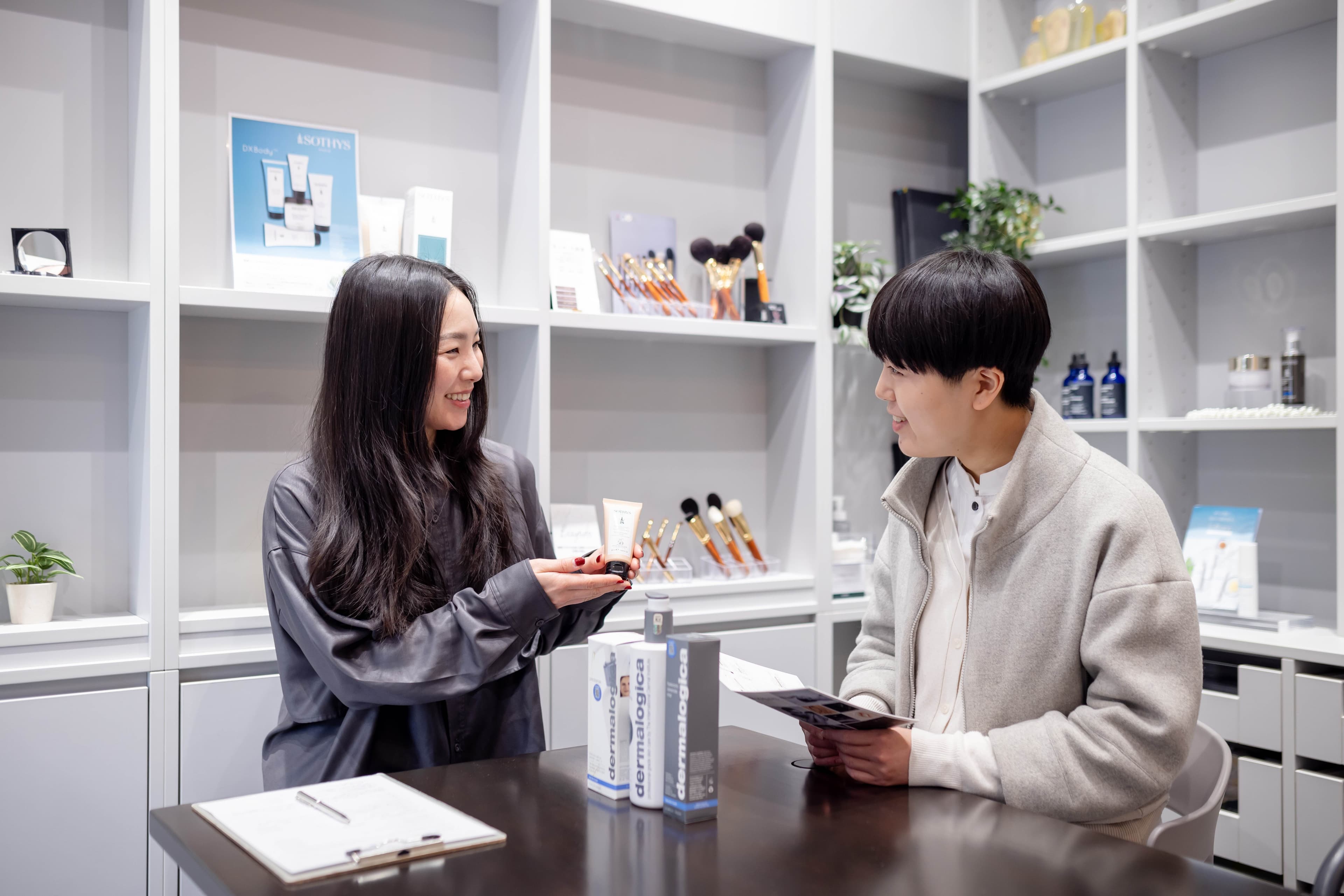カウンターでスタッフとお客様がDermalogica製品について会話しながら、購入について相談している様子